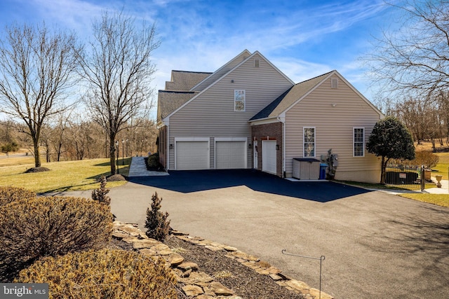 view of side of property with driveway, an attached garage, and fence