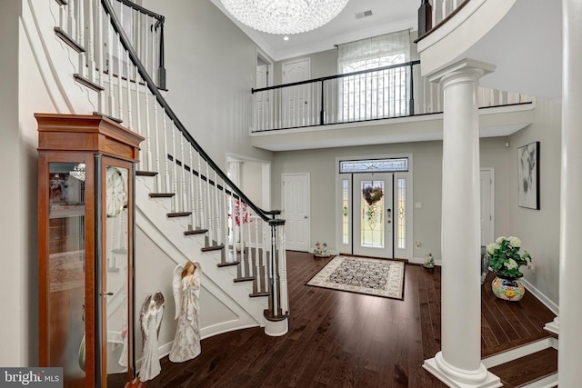 foyer entrance with baseboards, visible vents, ornate columns, and wood finished floors