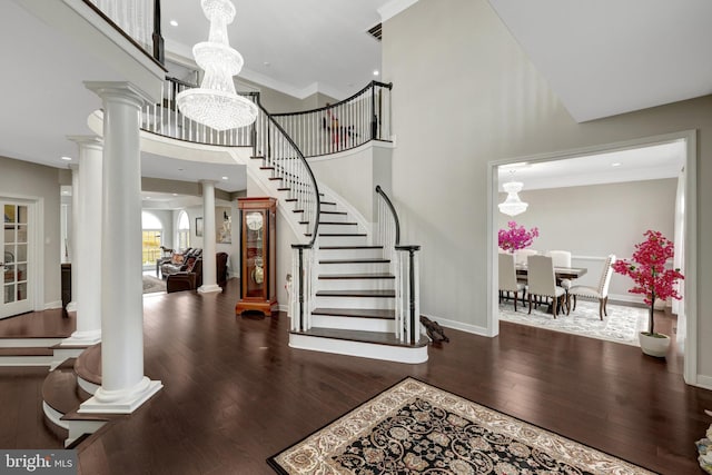 foyer featuring a notable chandelier, decorative columns, stairway, hardwood / wood-style floors, and baseboards