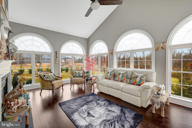 sunroom with a wealth of natural light, a glass covered fireplace, vaulted ceiling, and ceiling fan