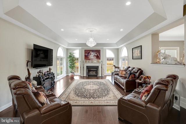 living room featuring a raised ceiling, baseboards, a fireplace, and dark wood-style flooring