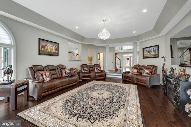 living room featuring dark wood-style floors, stairs, a tray ceiling, and recessed lighting