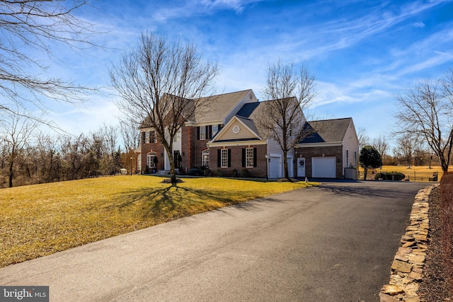 view of front of house with a garage, a front yard, brick siding, and aphalt driveway