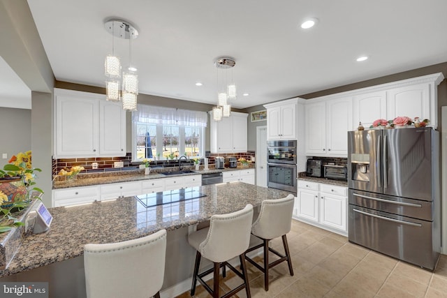 kitchen with stainless steel appliances, dark stone counters, white cabinets, and tasteful backsplash