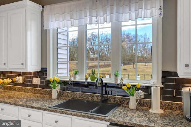 kitchen featuring tasteful backsplash, plenty of natural light, white cabinetry, and a sink