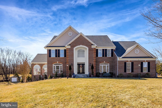 view of front of home featuring a shingled roof, a front lawn, and brick siding