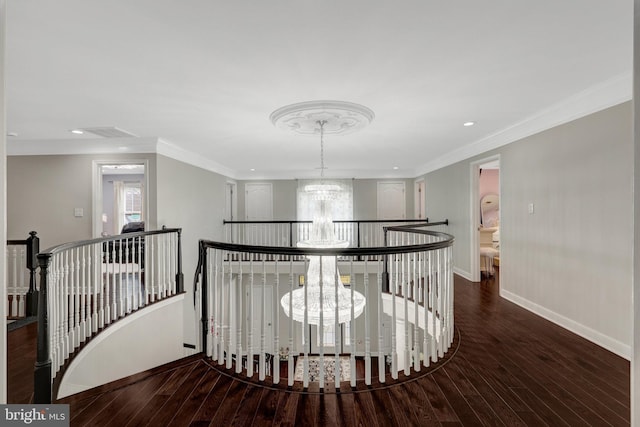 hallway with baseboards, wood finished floors, crown molding, an upstairs landing, and a chandelier