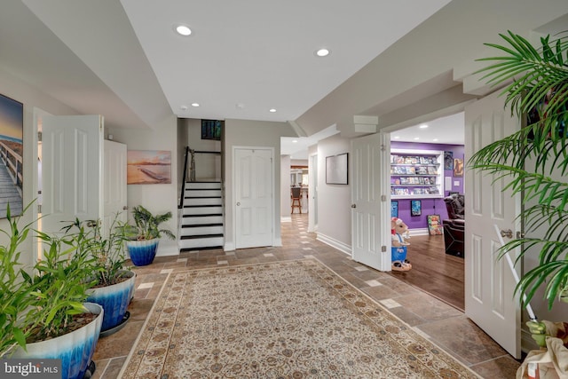 interior space featuring recessed lighting, stone tile flooring, baseboards, and stairs