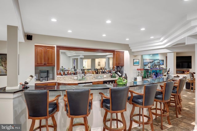 kitchen with a peninsula, a breakfast bar area, recessed lighting, and brown cabinets