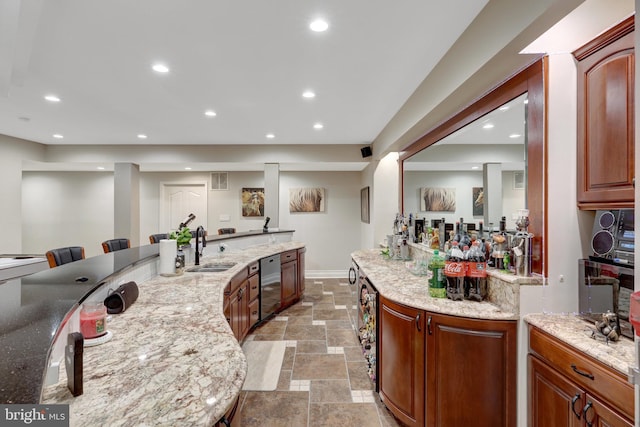 kitchen with light stone counters, recessed lighting, stone tile flooring, a sink, and baseboards