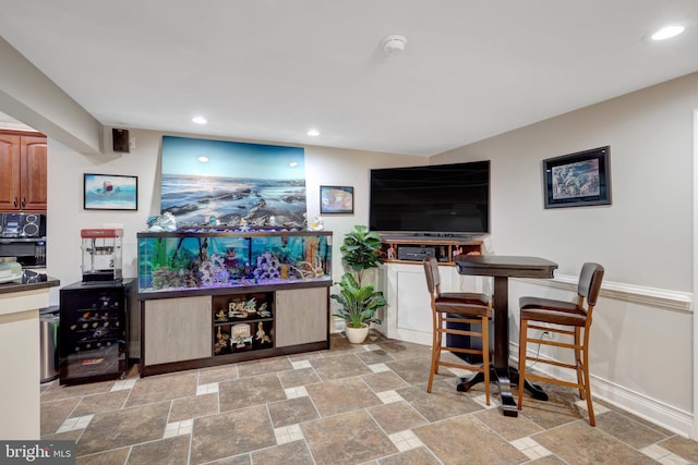 bar with black microwave, baseboards, stone tile flooring, and recessed lighting