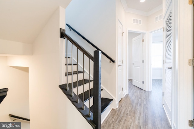 stairs with hardwood / wood-style flooring and ornamental molding