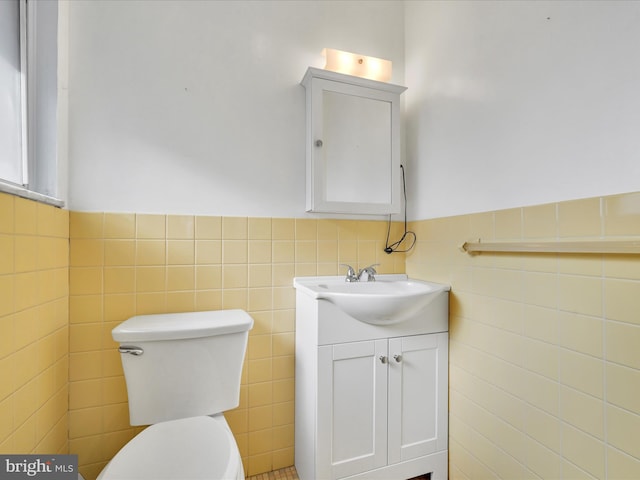 bathroom with vanity, tile walls, and toilet