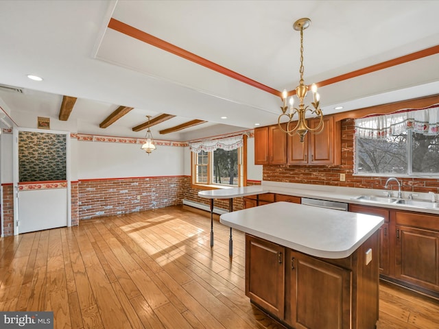 kitchen with sink, decorative light fixtures, a center island, and light wood-type flooring