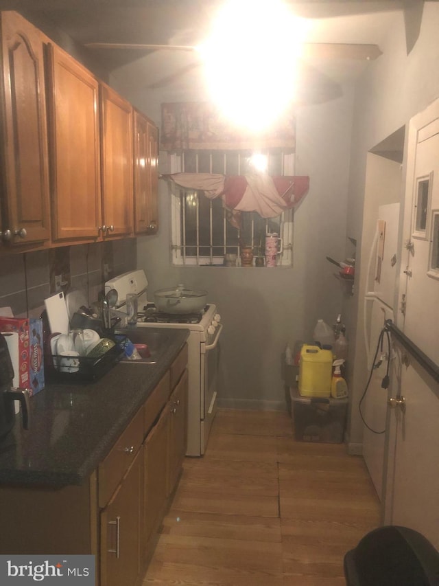 kitchen with white gas range, hardwood / wood-style floors, and backsplash