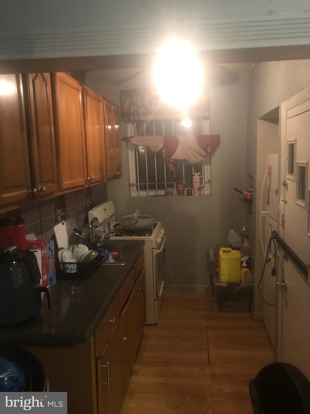 kitchen with hardwood / wood-style floors, decorative backsplash, and white gas stove