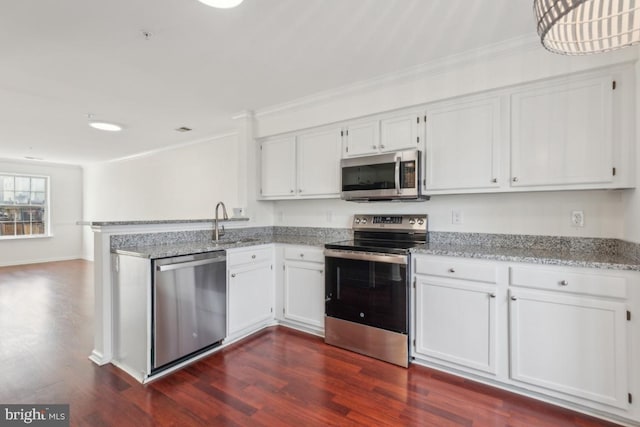 kitchen with dark wood-type flooring, sink, appliances with stainless steel finishes, kitchen peninsula, and white cabinets