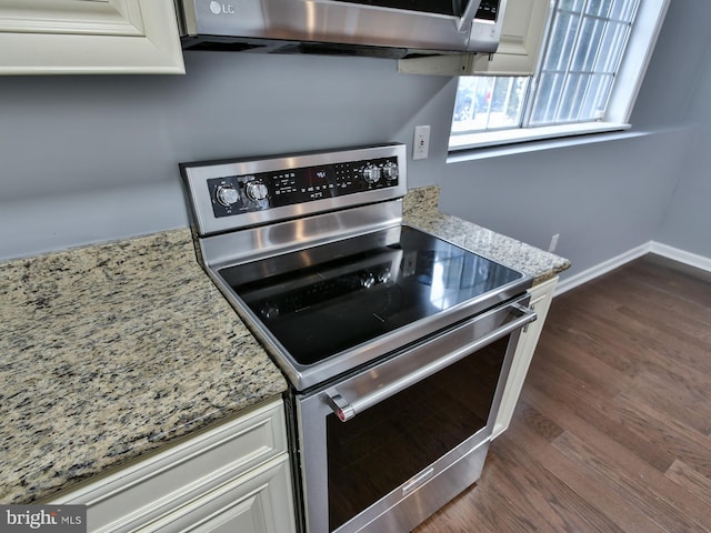 kitchen with white cabinetry, dark wood-type flooring, electric range, and light stone counters