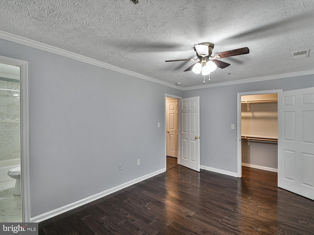 unfurnished bedroom featuring crown molding, ensuite bath, dark hardwood / wood-style floors, a spacious closet, and a closet