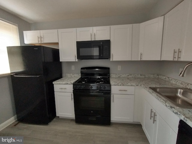 kitchen with sink, white cabinets, light hardwood / wood-style floors, black appliances, and light stone countertops