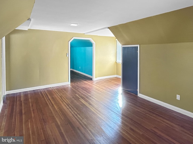 additional living space with vaulted ceiling and dark hardwood / wood-style flooring