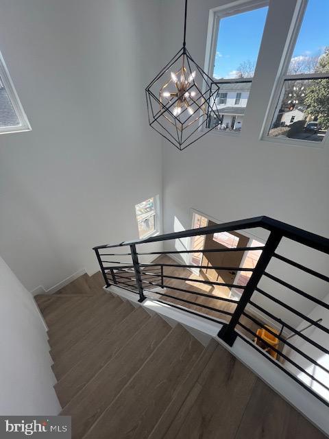 stairs featuring a chandelier and wood finished floors