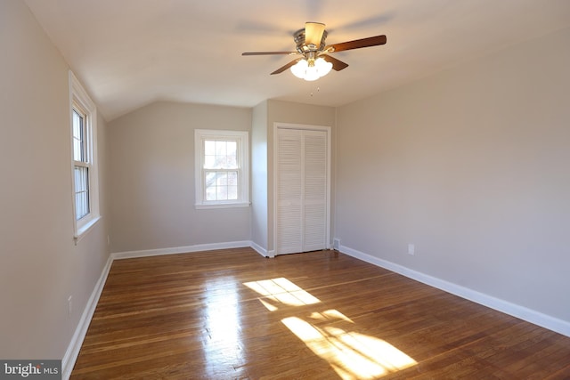 unfurnished bedroom featuring dark wood-type flooring, ceiling fan, vaulted ceiling, and a closet