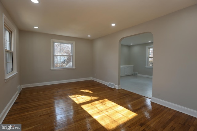 unfurnished room featuring dark wood-type flooring and a healthy amount of sunlight