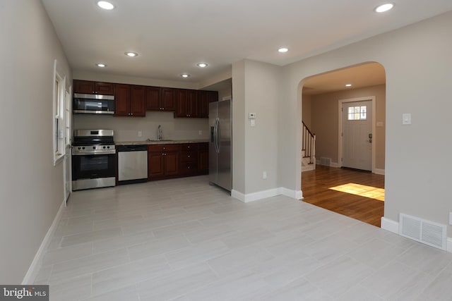 kitchen featuring stainless steel appliances, sink, dark brown cabinetry, and light hardwood / wood-style flooring