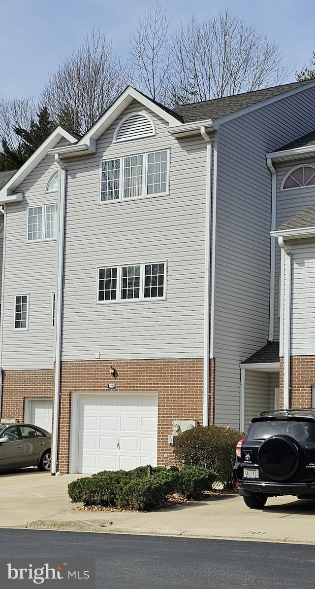 view of front of property featuring brick siding, concrete driveway, and an attached garage