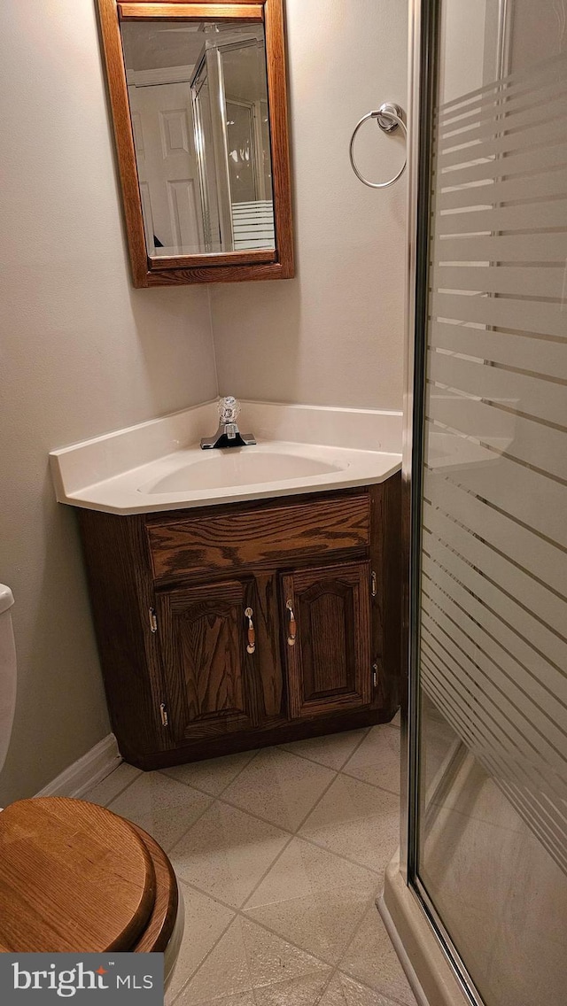 bathroom with vanity, toilet, baseboards, and a stall shower