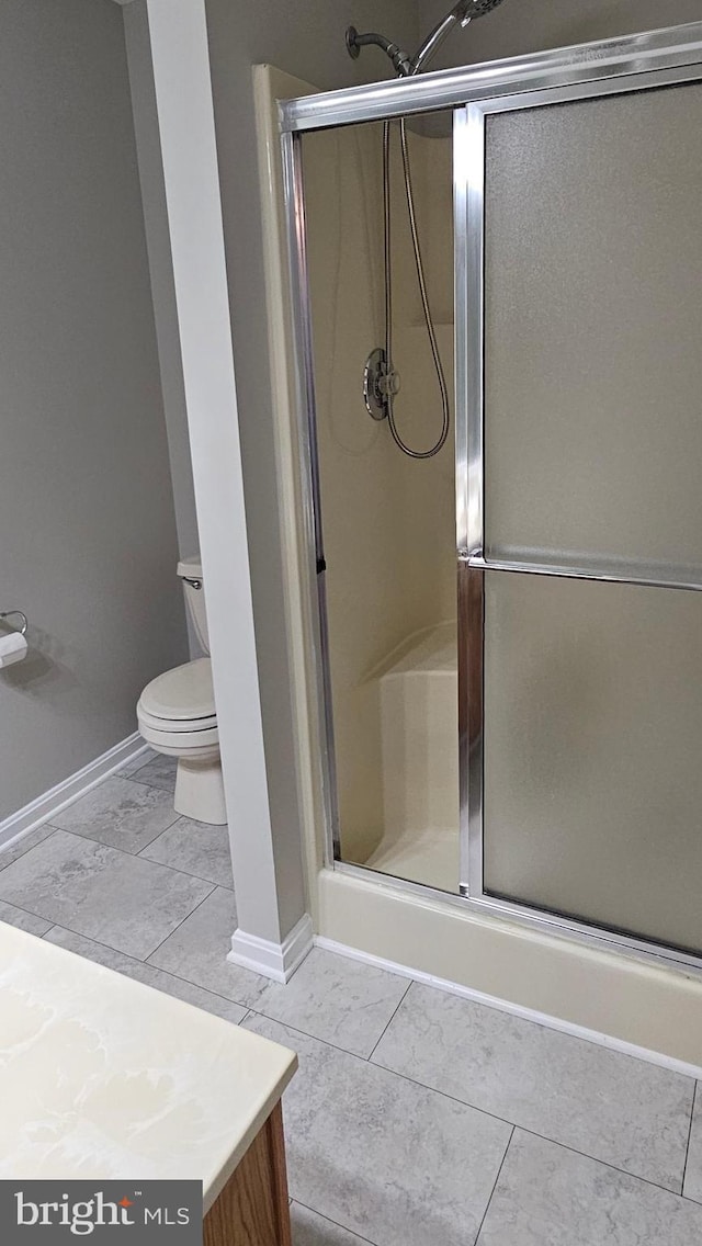 bathroom featuring baseboards, vanity, toilet, and a shower stall