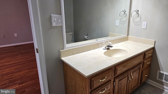 bathroom featuring visible vents, toilet, vanity, and baseboards