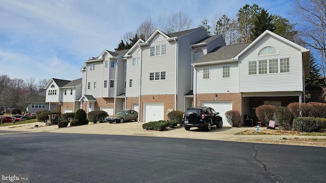 multi unit property featuring brick siding, a residential view, driveway, and an attached garage