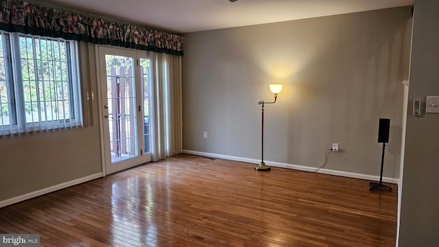 spare room with baseboards and wood-type flooring