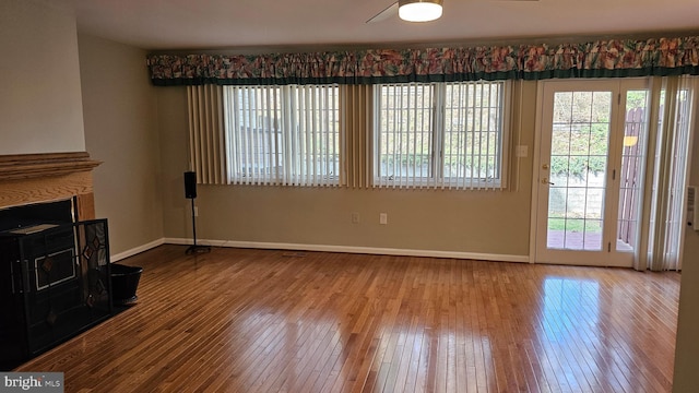 unfurnished living room featuring baseboards, wood-type flooring, and a fireplace