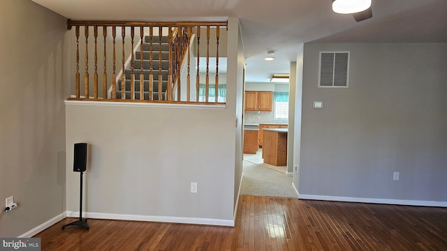 empty room featuring visible vents, baseboards, hardwood / wood-style floors, and stairway