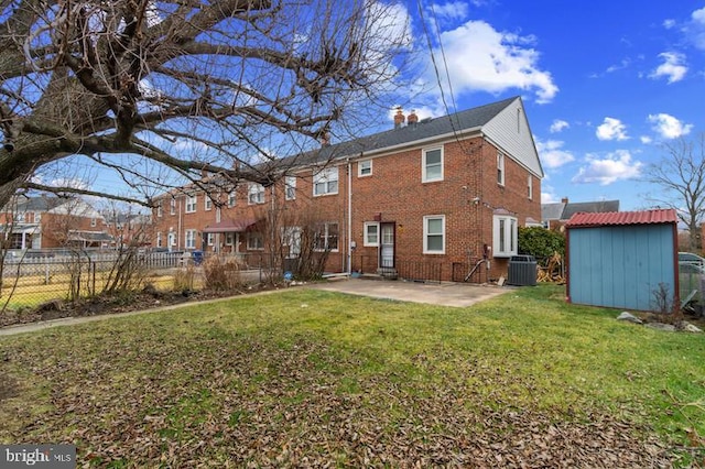 rear view of property featuring an outbuilding, a patio, a storage shed, brick siding, and fence