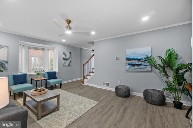 living area with stairway, wood finished floors, visible vents, and baseboards