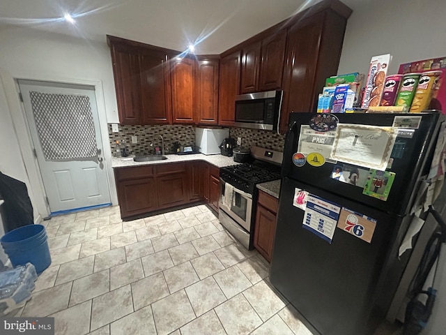 kitchen with appliances with stainless steel finishes, sink, decorative backsplash, and light tile patterned floors