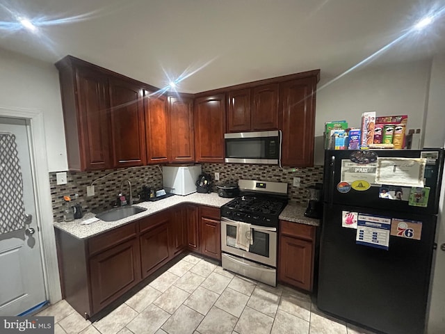 kitchen with appliances with stainless steel finishes, sink, light tile patterned floors, and decorative backsplash