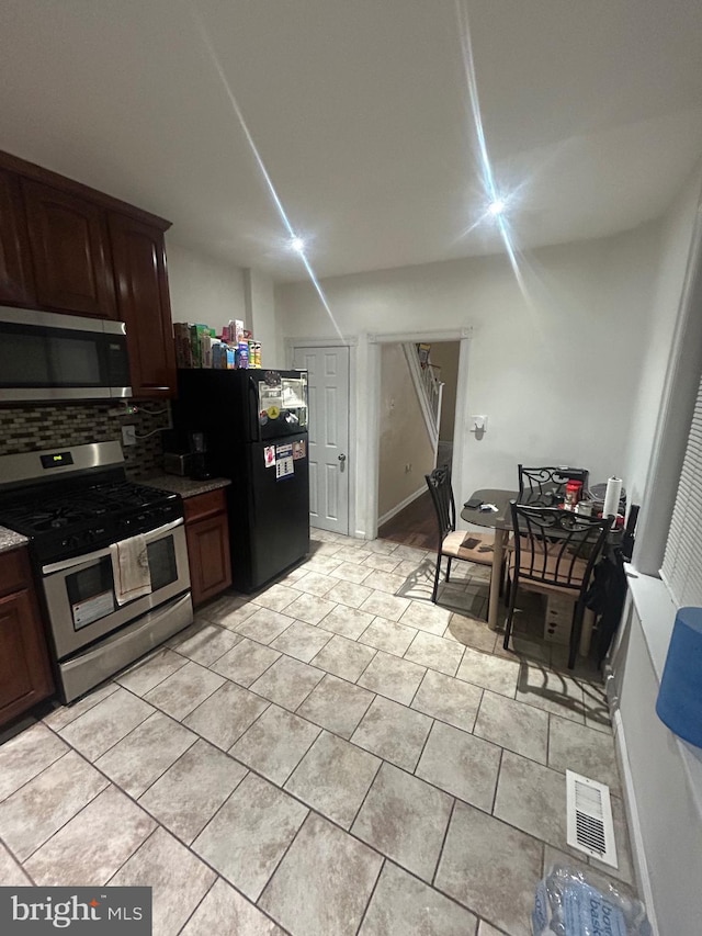 kitchen featuring dark brown cabinetry, backsplash, light tile patterned floors, and stainless steel appliances