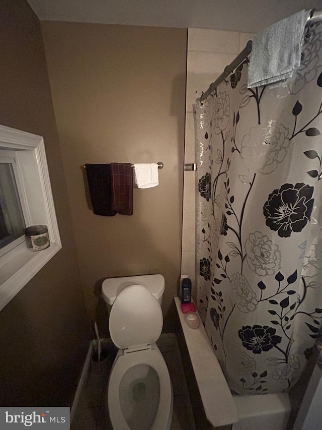 bathroom featuring shower / tub combo with curtain and toilet