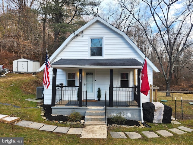 bungalow-style home featuring central AC, covered porch, and a storage unit