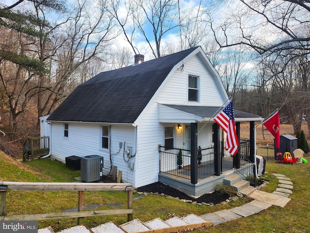 view of front of property with central AC, a front yard, and a porch