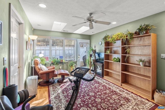 interior space with ceiling fan, hardwood / wood-style floors, a textured ceiling, and a skylight