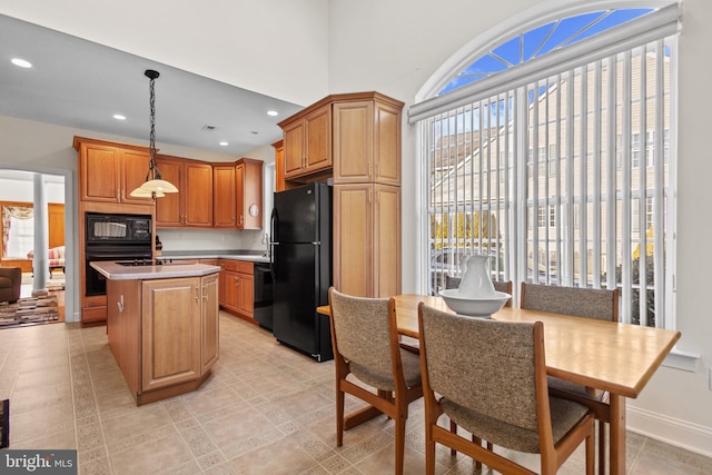 kitchen featuring a kitchen island, hanging light fixtures, and black appliances