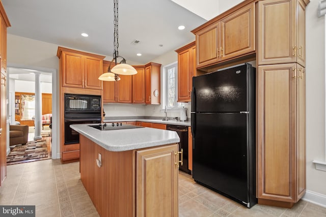 kitchen featuring decorative light fixtures, ornate columns, a kitchen island with sink, and black appliances