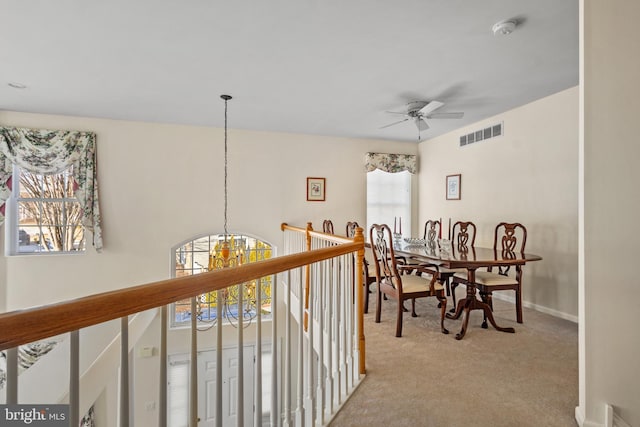 dining space with light carpet and ceiling fan with notable chandelier