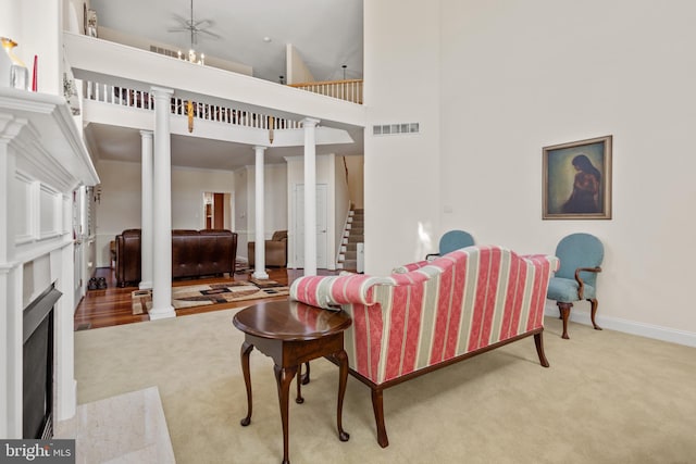 carpeted living room with ornate columns and a high ceiling